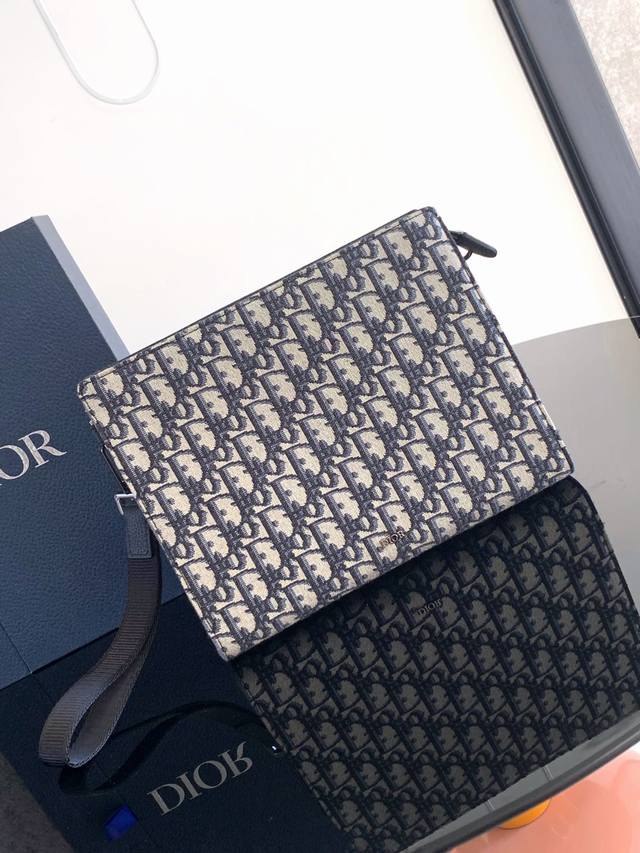 This Clutch Is A Signature Piece From Dior. Crafted From Beige And Black Oblique