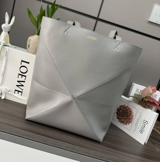 LwThe new large shiny cow leather Puzzle Fold handbag draws inspiration from the