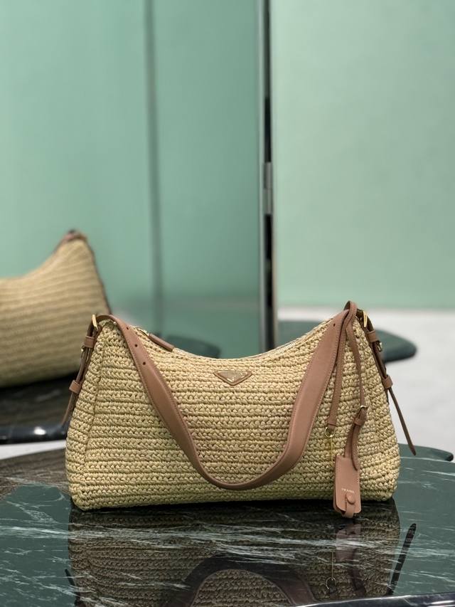 The Aimee Hobo is a simple, hand-woven raffia bag featuring a metal triangular e