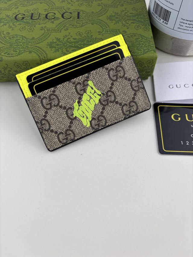 Guccl This two-tone card holder is crafted from coated fabric with the iconic Gg