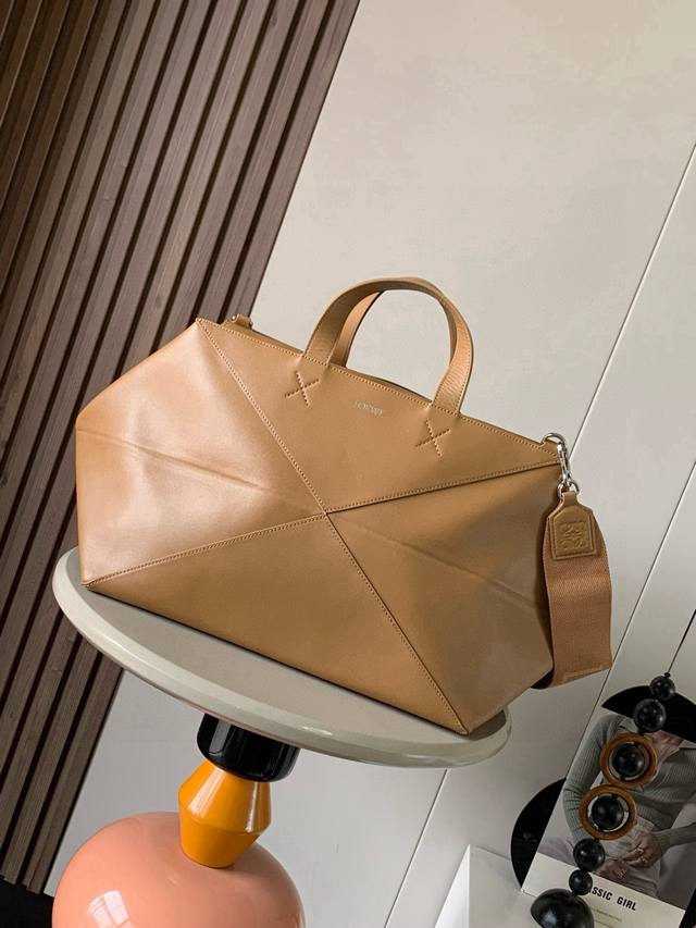 The new oversized shiny calfskin puzzle fold bag draws inspiration from the geom